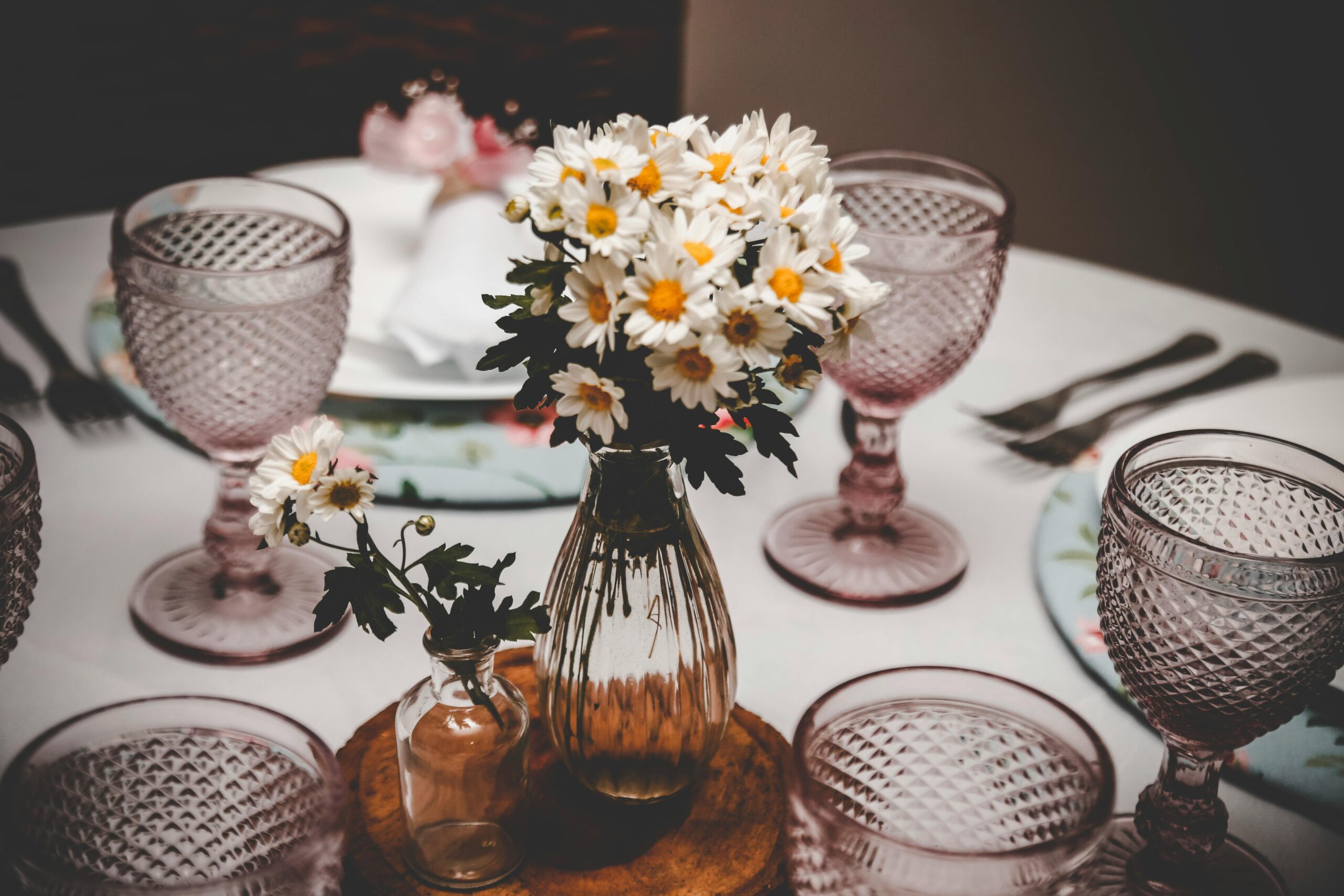 Charming table setup with vintage glasses and daisy flower arrangement, perfect for elegant dining occasions.