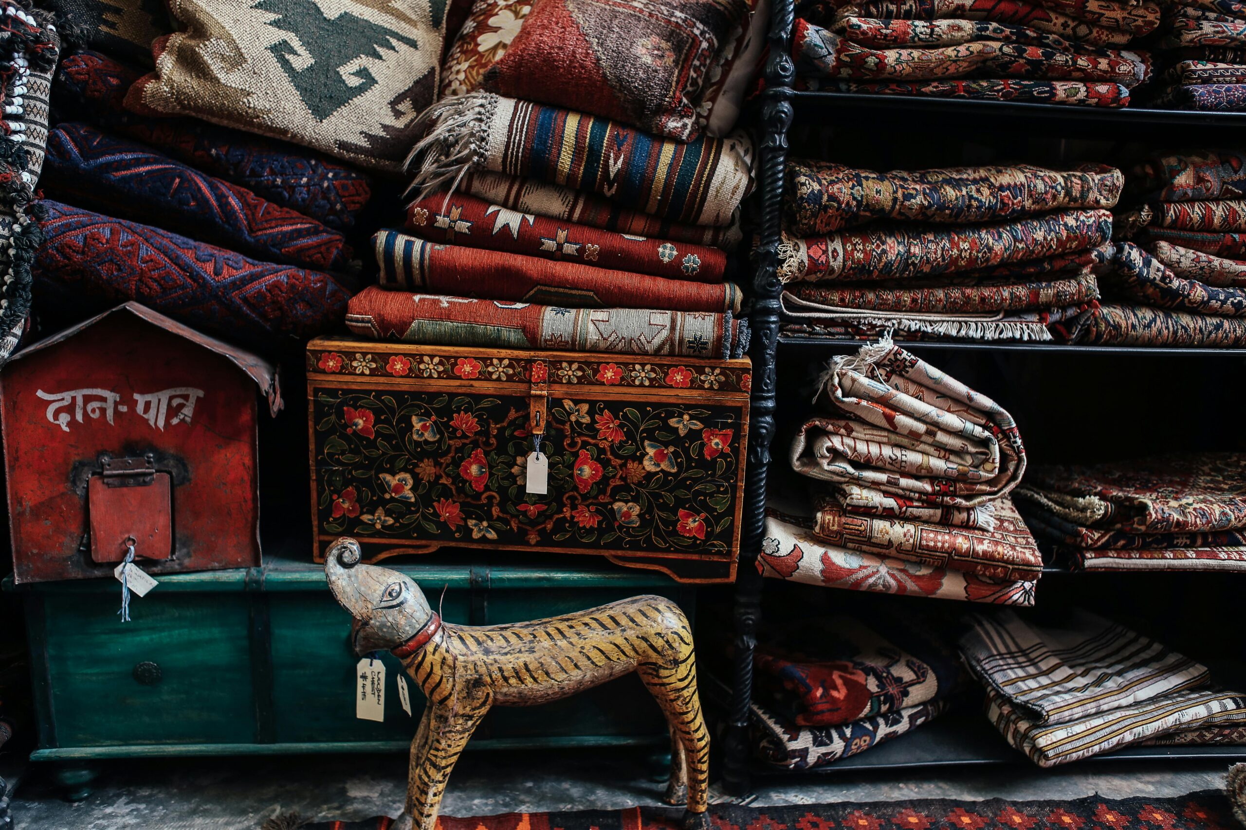 A vibrant collection of handmade textiles and rugs displayed in a rustic store setting.